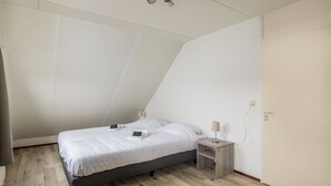 A bedroom with a bed, bedside tables, a lamp, and a ceiling light fixture.