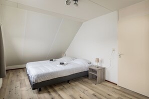 A bedroom with a bed, bedside tables, a lamp, and a ceiling light fixture.