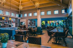 Cozy gathering space with multiple seating areas, a bar, and artwork on the walls.