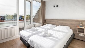 Et moderne hotelværelse med en stor seng, et vindue med udsigt og et lille natbord med en lampe.