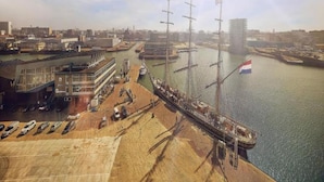 Une zone riveraine comprenant un quai, un bâtiment à la façade en verre et un drapeau.