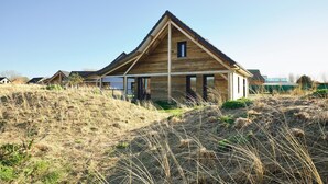 A modern wooden house with a triangular roof, surrounded by dry grass and a clear sky. - Comfortable Villa in Berck (Berck-Sur-Mer)