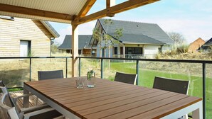 A wooden deck with a table and chairs, overlooking a grassy yard and neighboring houses. - Beach House in France near the Coast (Berck-Sur-Mer)