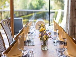 A dining table set with chairs, a vase with flowers, and clear glassware. - Penthouse Apartment with Mountain Views (Neukirchen am Großvenediger)