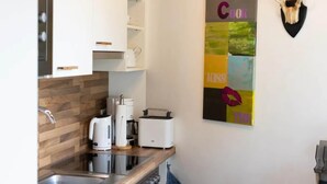 Une cuisine moderne avec des meubles blancs, un plan de travail en bois et une machine à café.