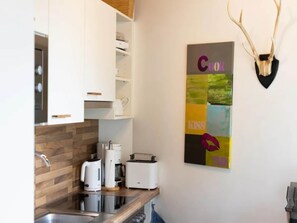 A modern kitchen with white cabinets, a wooden countertop, and a coffee maker. - Penthouse Apartment with Mountain Views (Neukirchen am Großvenediger)