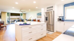 A modern kitchen with a central island, stainless steel appliances, and a dining area with a view.