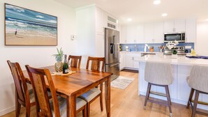 A modern kitchen with white cabinets, stainless steel appliances, and a blue backsplash.