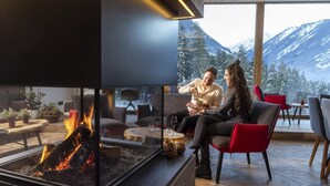 A modern interior with a fireplace, comfortable seating, and a view of snow-capped mountains.