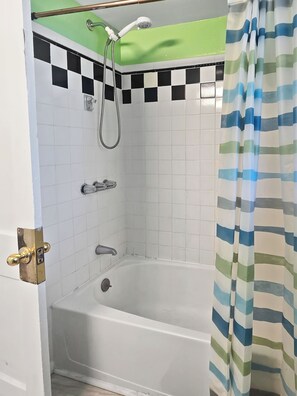 A bathroom with a bathtub, a shower, and a green wall. - Downtown 3 Bedroom gound level condo - 1 block from beach, boardwalk and Atlantic Ocean! Beach Roost (Ocean City)