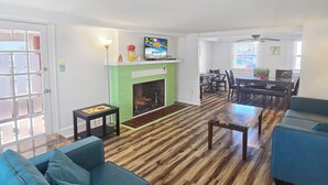 Un salon avec une cheminée, un coin repas et un espace détente avec un canapé bleu.
