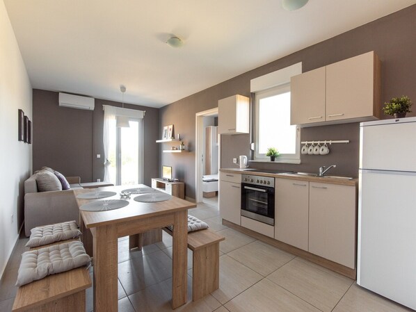 A modern kitchen with a dining area, built-in appliances, and a view of the outdoors.