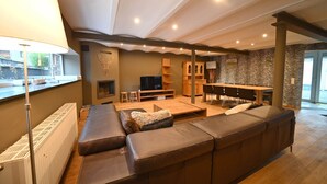 A modern living room with a large sectional sofa, a TV, and a fireplace. - Village House in Ambly with Outdoor Pool (Nassogne, Ambly)