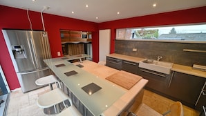 A modern kitchen with a central island, stainless steel appliances, and a red accent wall. - Village House in Ambly with Outdoor Pool (Nassogne, Ambly)