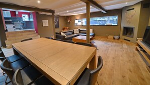 A modern living room with a wooden dining table, black chairs, a leather sofa, and a fireplace. - Village House in Ambly with Outdoor Pool (Nassogne, Ambly)