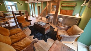 A rustic interior with wooden furniture, a bar area, and a staircase. - Village House in Ambly with Outdoor Pool (Nassogne, Ambly)