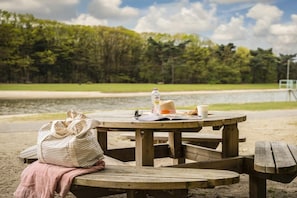 A picnic table with a bag, a bottle, a hat, and a cup on it.