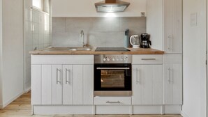 Una cocina moderna con horno empotrado, extractor de acero inoxidable y cafetera sobre la encimera.