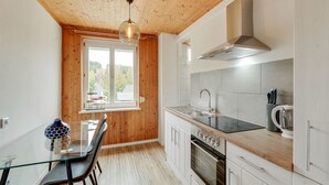 Una cocina moderna con techo de madera, un comedor con mesa de vidrio y vistas al exterior.