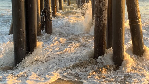 Une structure de jetée composée de poutres en bois et de supports métalliques qui s’étendent dans l’eau.