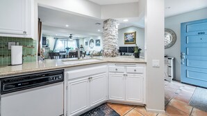 Une cuisine moderne avec des meubles blancs, un lave-vaisselle et un mur décoratif en pierre.