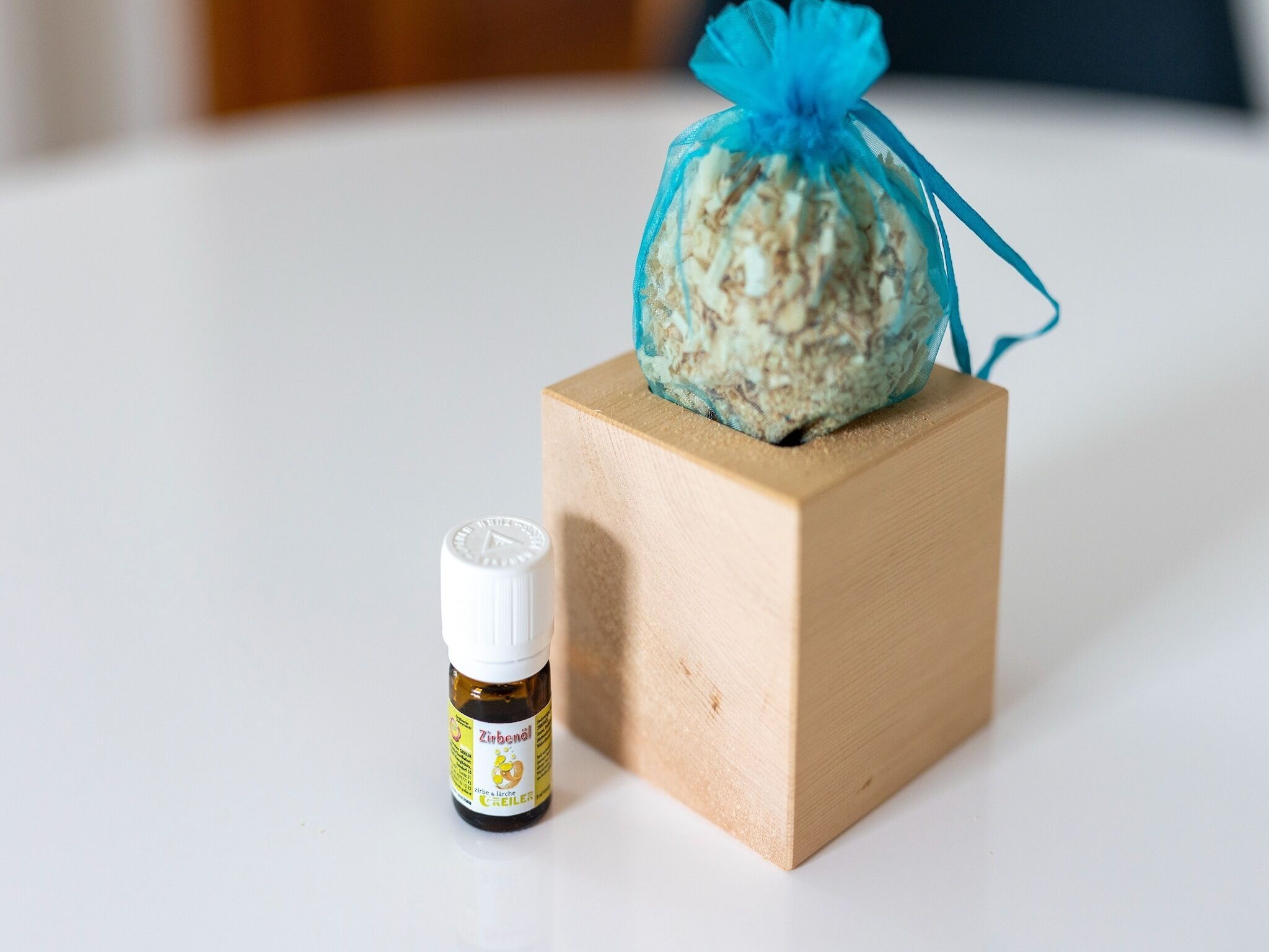 Un petit bloc de bois sur lequel repose un sac en tissu bleu, et à côté, une petite bouteille de Zineboll.