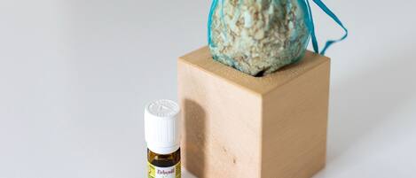 Un petit bloc de bois sur lequel repose un sac en tissu bleu, et à côté, une petite bouteille de Zineboll.