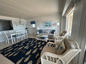 A living room with a sofa, chairs, a coffee table, and a rug with fish patterns.