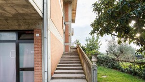 Una escalera conduce a la entrada de un edificio con fachada de ladrillo y puerta de vidrio.