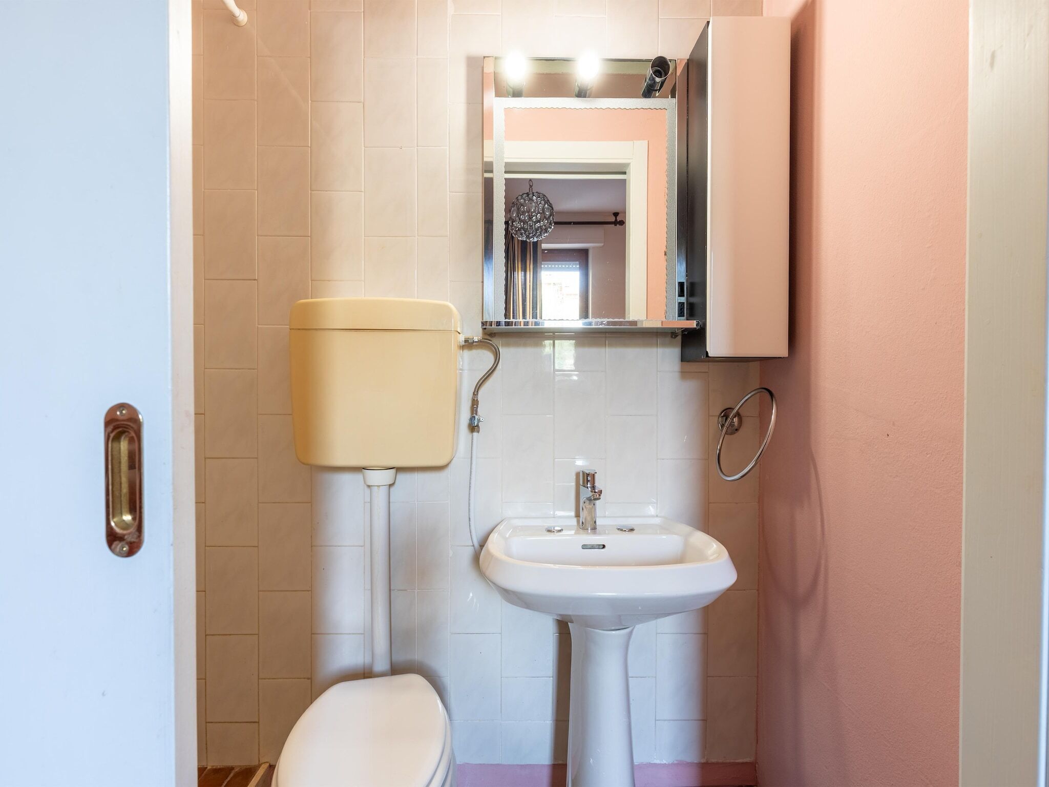 Un baño pequeño con inodoro, lavamanos y espejo.
