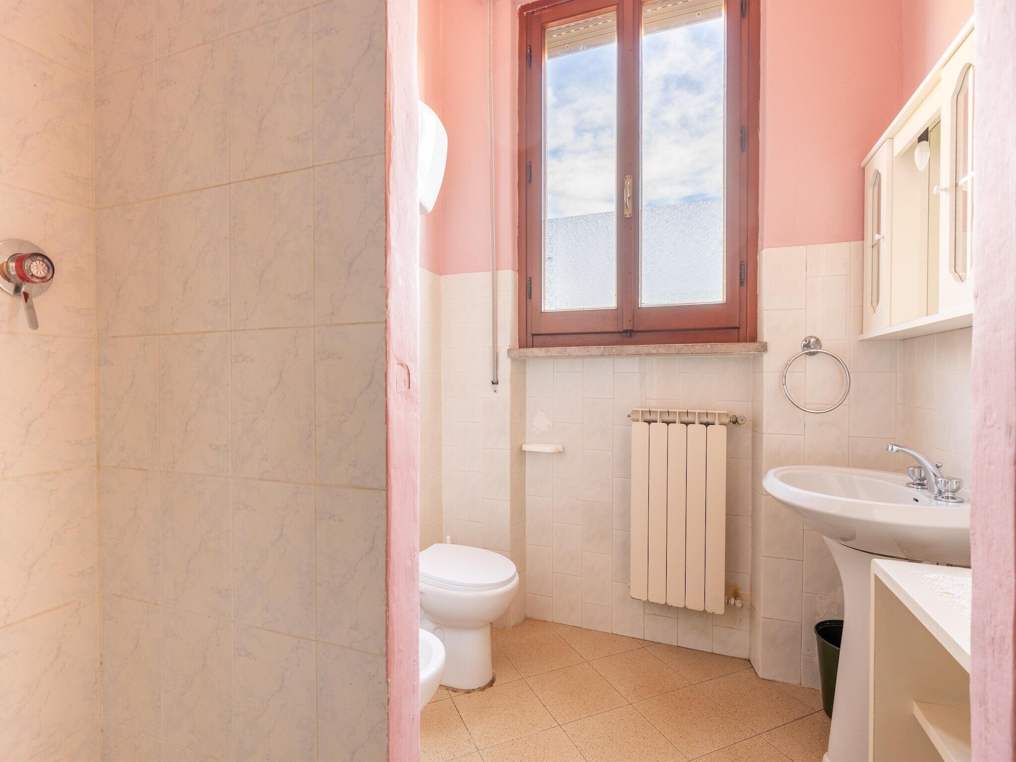 A bathroom with a toilet, sink, and window.