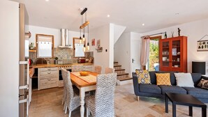 A spacious living area with a dining table, chairs, and a sofa. A kitchen with a tiled backsplash and a cabinet is visible in the background. - Villa in Bargemon with Pool and Mountain Views (Bargemon)
