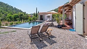 A swimming pool with lounge chairs, a small building, and a view of a forested hill. - Villa in Bargemon with Pool and Mountain Views (Bargemon)