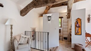 A spacious living area with a high ceiling, exposed wooden beams, a sofa with decorative pillows, a lamp, and a wall-mounted artwork. - Villa in Bargemon with Pool and Mountain Views (Bargemon)