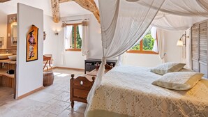 A bedroom with a canopy bed, wooden beams, a large window, and a painting on the wall. - Villa in Bargemon with Pool and Mountain Views (Bargemon)