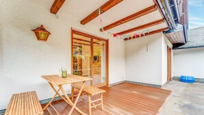A wooden deck with a table and benches, a glass door leading inside, and a blue container on the ground. - Spacious flat in Adenau near the Nürburgring (Adenau)