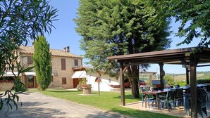 Una villa rústica con un patio, mobiliario exterior y vistas al campo.