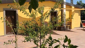 Un bâtiment jaune doté d’un patio, d’une porte et d’une petite table entourée de chaises.