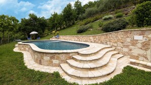 A swimming pool with stone steps and a lounge chair.