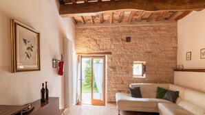 A cozy living room with a stone wall, a wooden ceiling, a white sofa, and a framed botanical print.
