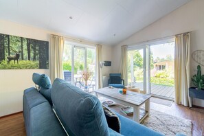 A modern living room with a blue sofa, a coffee table, and a painting of a deer. - Holiday Home in Voorthuizen near Veluwe Forest (Voorthuizen)