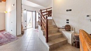 Un hall d’entrée spacieux, agrémenté d’un escalier en bois, d’un tapis à motifs et d’une porte donnant sur un espace extérieur.
