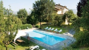 Una piscina con sillas de descanso y una casa al fondo.