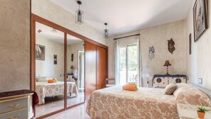 Un dormitorio con una cama grande, un escritorio con silla, un armario y una ventana con cortinas.