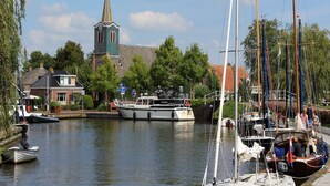 Un canal bordé de bateaux, une église et une rangée de maisons.