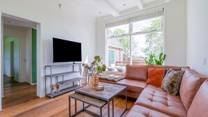 Un salon moderne doté d’un grand téléviseur à écran plat, d’un canapé en cuir, d’une table basse et offrant une vue sur l’extérieur.
