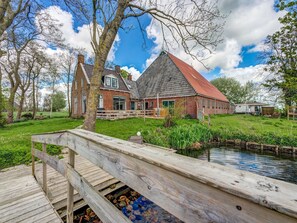 Traditional Dutch-style house with a brick facade and wooden deck overlooking a serene pond.