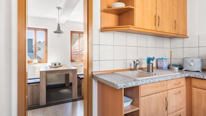Une cuisine avec des meubles en bois, un plan de travail en granit et une fenêtre donnant sur une maison.