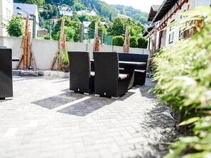 Een terras buiten met rieten meubilair en een barbecue.