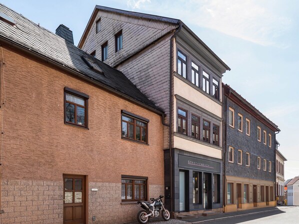 Een meerlaags gebouw met een bakstenen gevel, een motorfiets ervoor en een winkel met een bord.